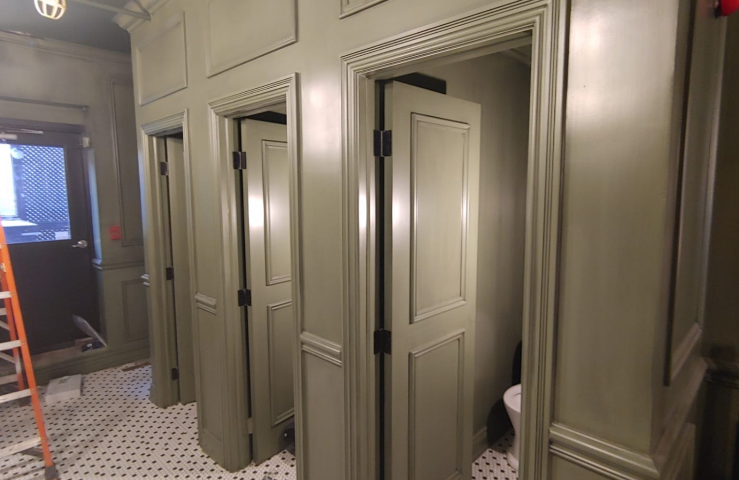 A bathroom with green walls and doors.