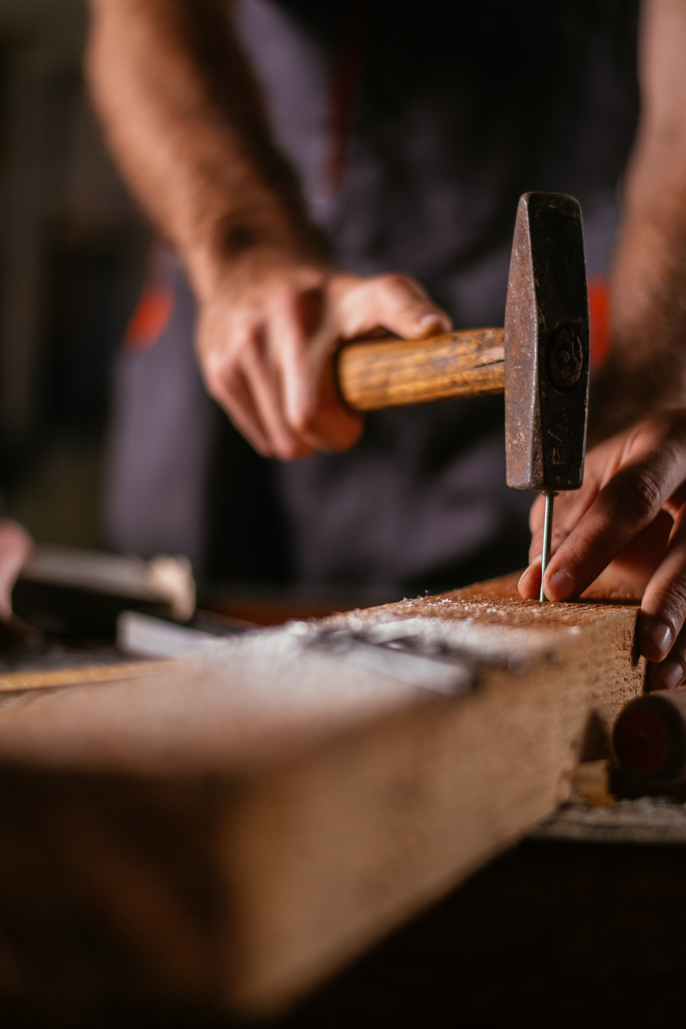 A man is hammering a piece of wood.