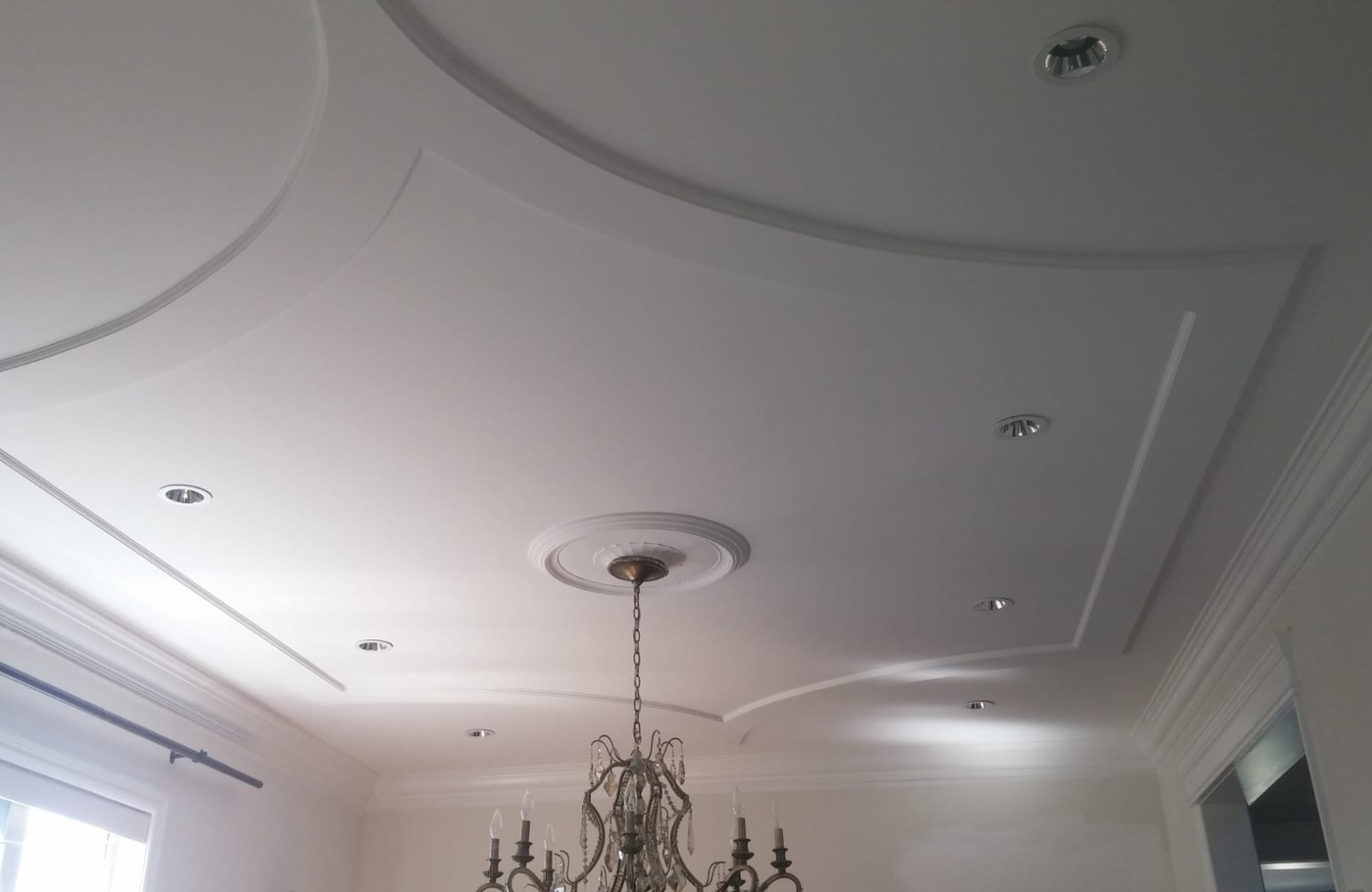 A dining room with a chandelier and white ceiling.